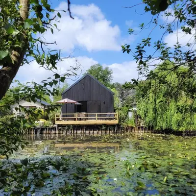 a building on a dock next to a pond at Vakantiewoning aan het water, vissen, wandelen en genieten in de natuur in Geel
