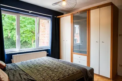 a bedroom with a bed and two windows at Chez Marraine Suzanne in Liège