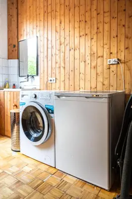 a washing machine in a kitchen with wooden walls at Chez Marraine Suzanne in Liège