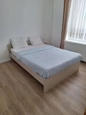 a bed in a white room with a wooden floor at Maison sympa in Liège