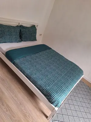 a bed with a green blanket on top of it at Maison sympa in Liège