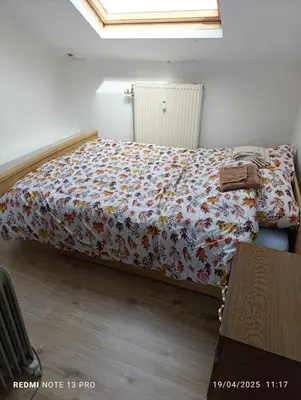 a bedroom with a bed with a floral comforter at résidence KAKIKA in Verviers