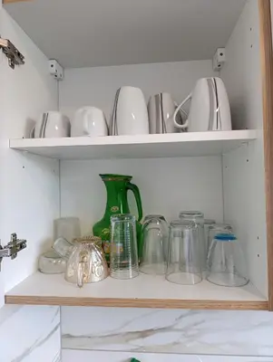 a shelf filled with dishes and a green vase at résidence KAKIKA in Verviers