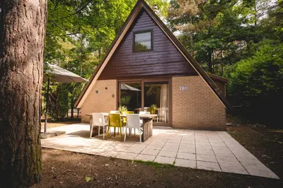 a patio with a table and chairs in front of a house at Boshuisje Rekem - Kitoko in Lanaken