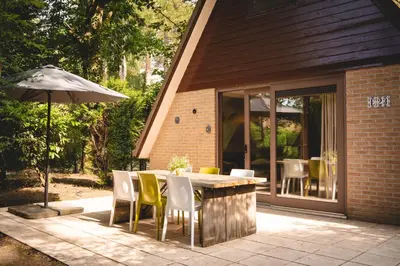 a patio with a table and chairs and an umbrella at Boshuisje Rekem - Kitoko in Lanaken