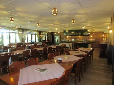 a restaurant with wooden tables and chairs and a kitchen at Hotel De Watermolen in Bocholt
