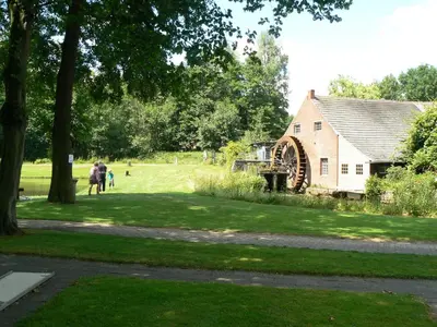 a group of people walking in a park next to a barn at Hotel De Watermolen in Bocholt