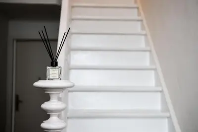 a white staircase with a vase with sticks in it at Cozy Home Liege in Liège