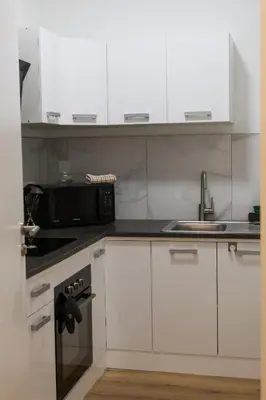 a kitchen with white cabinets and a sink and a microwave at Cozy Home Liege in Liège