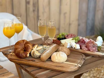 a tray of bread and wine glasses on a wooden table at Wellness B&B Essential by Cin in Zonhoven