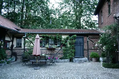 a patio with an umbrella and chairs and a house at Hof ter Wallen in Zoutleeuw