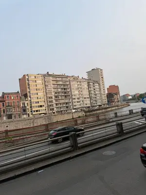 a car driving on a highway with buildings in the background at Luxury Riverfront Apartment near La Meuse in Liège