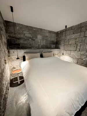 a large white bed in a room with a stone wall at La Tour in Liège