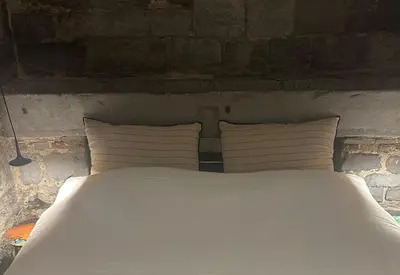 a white bed with four pillows and a brick wall at La Tour in Liège