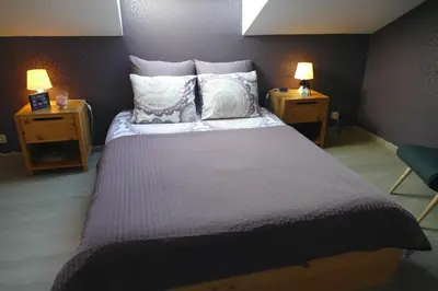 a bedroom with a large bed with pillows and two lamps at Aux Cosmos in Olne