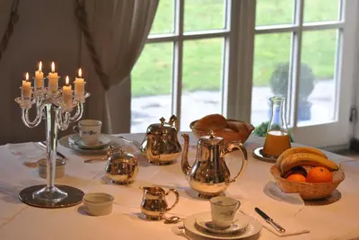 a table with candles and tea pots and a table cloth at Aux Cosmos in Olne