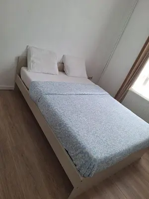 a bedroom with a bed with a blue comforter and a window at Maison sympathique in Liège