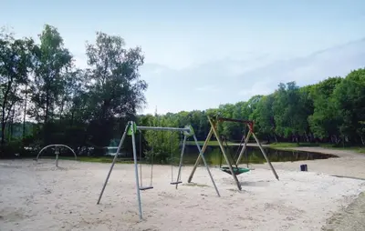 an empty playground with two swings in the sand at Bungalow in Sonnevijver - Hoge kempen in Lanaken