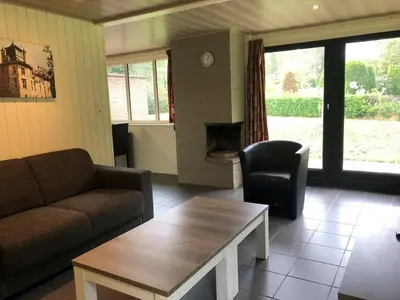 a living room with a couch and a table and a fireplace at Bungalow in Sonnevijver - Hoge kempen in Lanaken