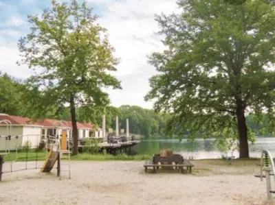 a park with a picnic table and a playground next to a lake at Bungalow in Sonnevijver - Hoge kempen in Lanaken