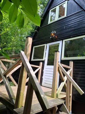a black house with a white door and a wooden porch at Bosrijk gelegen vakantiehuis met optimale privacy! in Lanaken