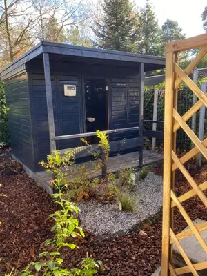 a black outhouse with a fence in a garden at heerlijk vakantie huis Lovely holiday home in Lanaken