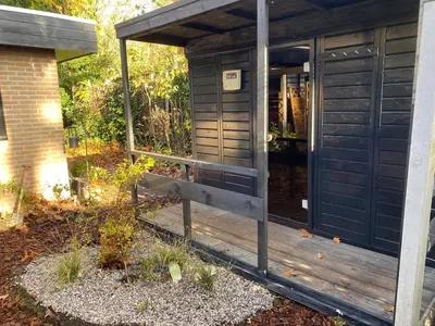 a wooden outhouse with a wooden porch at heerlijk vakantie huis Lovely holiday home in Lanaken