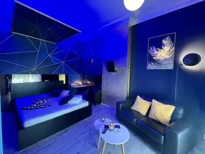 a blue room with a bed and a couch and a table at Le Vénitien in Liège