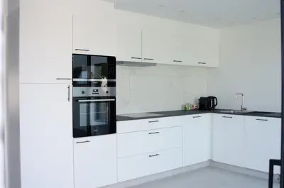 a white kitchen with white cabinets and black appliances at Vakantiewoning Ten Huyze Bucholt met tuinsauna in Bocholt