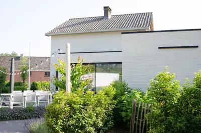 a white house with white chairs in a garden at Vakantiewoning Ten Huyze Bucholt met tuinsauna in Bocholt