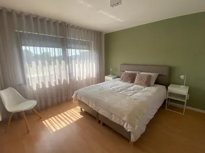 a bedroom with a bed and a chair and a window at Vakantiewoning Ten Huyze Bucholt met tuinsauna in Bocholt