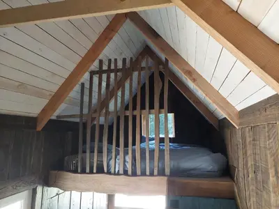 a bed in the attic of a wooden house at Mirabel - DreamsCanGrow in Hasselt