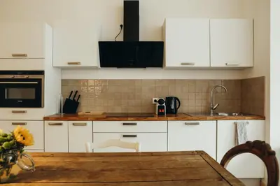 a kitchen with white cabinets and a wooden table at Beauvoir, Parc de la Boverie by WelcHome in Liège