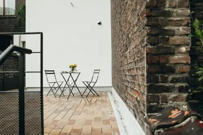 a brick wall next to a table with chairs at Beauvoir, Parc de la Boverie by WelcHome in Liège