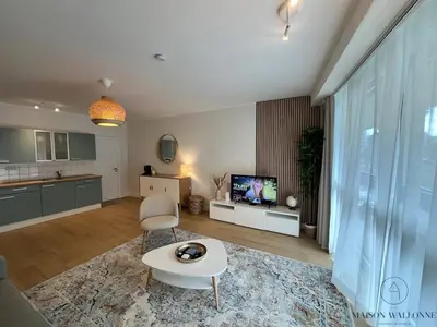 a living room with a couch and a table and a tv at Open Design apartment in Liège