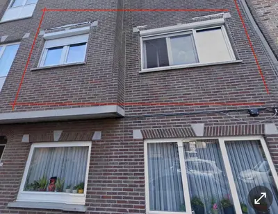 a tall brick building with four windows on it at Heel Appartement 90m2 met 2 slaapkamers woonkamer Keuken badkamer privé garage in Sint-Truiden