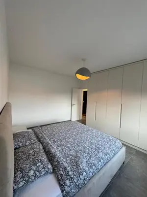 a bedroom with a large bed and a light at Heel Appartement 90m2 met 2 slaapkamers woonkamer Keuken badkamer privé garage in Sint-Truiden