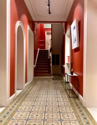 a hallway with red walls and a staircase with a tile floor at Crossborder Nest - Appartement de standing proche du circuit SPA-FRANCORCHAMPS et des HAUTES-FAGNES in Verviers