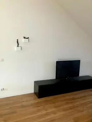 a living room with a flat screen tv on a table at Crossborder Nest - Appartement de standing proche du circuit SPA-FRANCORCHAMPS et des HAUTES-FAGNES in Verviers