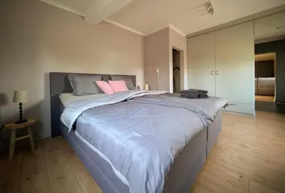 a bedroom with a large bed with pink pillows on it at Landbæne in Lommel