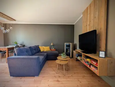 a living room with a blue couch and a tv at Landbæne in Lommel