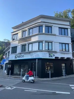 a man riding a scooter in front of a building at Bel appart - Tilff in Tilff