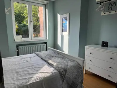 a bedroom with a bed and a dresser and two windows at Bel appart - Tilff in Tilff