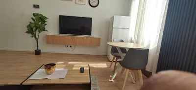 a living room with a table and a television at Appartement dans rue calme in Liège