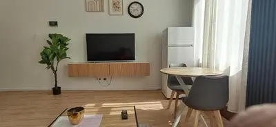 a living room with a table and a television at Appartement dans rue calme in Liège