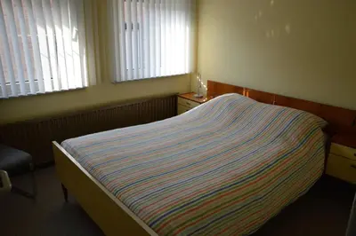 a bedroom with a bed and a chair and windows at Charming Belgian Getaway, vakantiewoning in Oudsbergen - 3 Bedrooms Garden in Oudsbergen