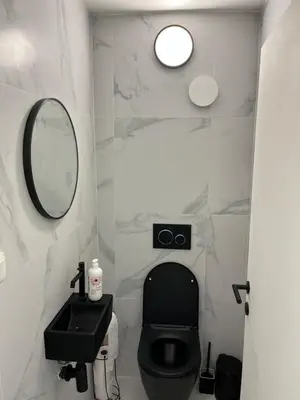 a bathroom with a black toilet and a mirror at DEDIA Guest Home