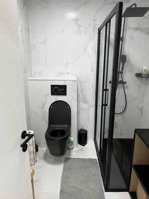 a bathroom with a black toilet and a shower at DEDIA Guest Home
