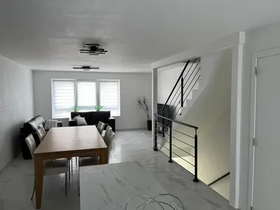 a living room with a table and a stair case at DEDIA Guest Home