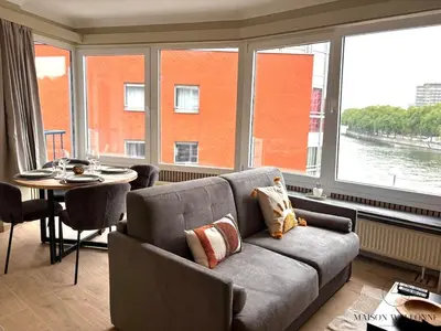a living room with a couch and a table and large windows at Le 180 escapade face à la Meuse in Liège